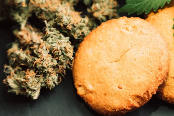 Cookies med marijuana. Godis med cannabis. Cannabis knoppar på en svart bakgrund. Bakning med tillägg av Cbd. godis med weed. — Stockfoto