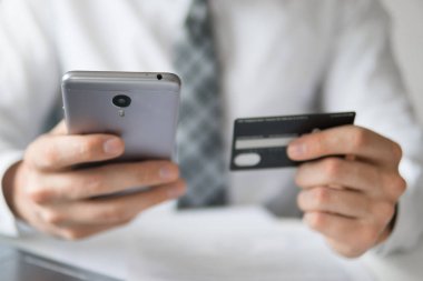 Akıllı telefon ve Internet ticareti. Online ödeme telefon aracılığıyla. Malların online ödeme. Genç işadamı onun elinde banka kredi kartıyla. Online Döviz Alım Satım ticaret.