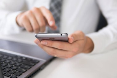 Açık renkli. İş adamı iş bilgisayar ile ofis işleri tablo. Akıllı telefon elinde tutuyor. Bir dizüstü bilgisayar ile ofis işleri. Mali iş.