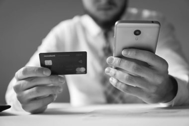 Genç işadamı onun elinde banka kredi kartıyla. Online ödeme telefon aracılığıyla. Online Döviz Alım Satım ticaret. Akıllı telefon ve Internet ticareti. Malların online ödeme.