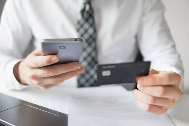 Malların online ödeme. Online Döviz Alım Satım ticaret. Akıllı telefon ve Internet ticareti. Online ödeme telefon aracılığıyla. Onun elinde banka kredi kartıyla genç işadamı.