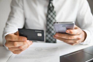 Akıllı telefon ve Internet ticareti. Genç işadamı onun elinde banka kredi kartıyla. Online Döviz Alım Satım ticaret. Malların online ödeme. Telefon aracılığıyla online ödeme.