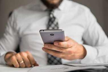 Bir dizüstü bilgisayar ile ofis işleri. Akıllı telefon elinde tutuyor. İş adamı iş bilgisayar ile ofis işleri tablo. Genç işadamı sakallı. Mali iş. Açık renkli.