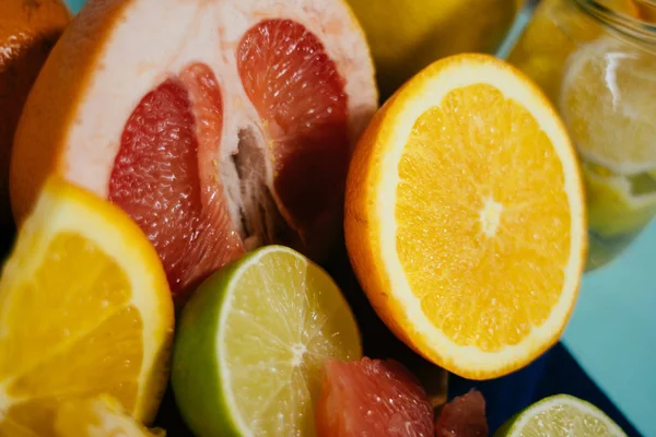 Agrumes, oranges, citrons, limes, pamplemousse, pomelo sur carton vintage, limonade et jus dans un verre sur fond turquoise — Photo