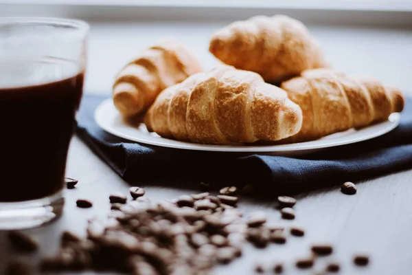 Dessert und Kaffeebohnen. Mate launische Farbe. Makroaufnahme von frischen Croissants und Kaffee auf schwarzem Hintergrund. das Konzept des Frühstücks. — Stockfoto