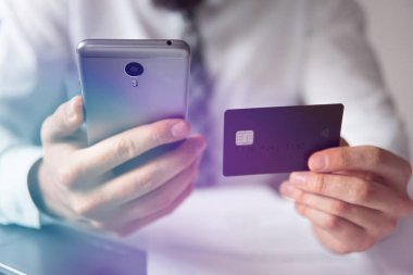 Online Döviz Alım Satım ticaret. Malların online ödeme. Akıllı telefon ve Internet ticareti. Genç işadamı onun elinde banka kredi kartıyla. Telefon aracılığıyla online ödeme.