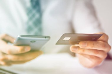 İşadamı bir smartphone ve kredi kartı online ödeme için kullanır. Office iş kavramı. Telefonu kapatın. Beyaz arka plan. Gönderen e-posta, hareket eden telefon. Online alışveriş. Işık sızıntıları