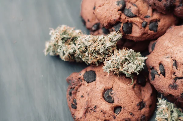 Bakken met de toevoeging van Cbd. snoep met onkruid. Chocolade koekjes met marihuana. Snoep met cannabis. Cannabis toppen op een zwarte achtergrond. — Stockfoto