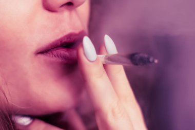 Bir kadın sigara ot esrar esrar ve onun elinde bir çakmak. Siyah bir arka plan üzerinde duman. Tıbbi esrar kullanım ve yasallaştırma esrar kavramları. Pembe siyah bir arka plan renklendirme