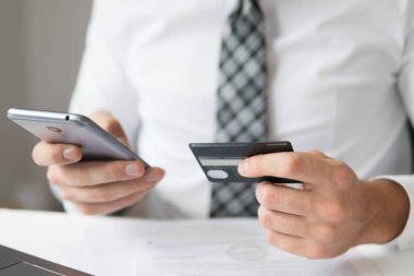 Malların online ödeme. Online Döviz Alım Satım ticaret. Akıllı telefon ve Internet ticareti. Genç işadamı onun elinde banka kredi kartıyla. Telefon aracılığıyla online ödeme.