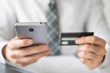 Online ödeme telefon aracılığıyla. Malların online ödeme. Online Döviz Alım Satım ticaret. Akıllı telefon ve Internet ticareti. Onun elinde banka kredi kartıyla genç işadamı.