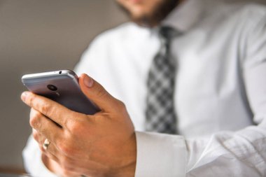 Mali iş. İş adamı iş bilgisayar ile ofis işleri tablo. Akıllı telefon elinde tutuyor. Genç işadamı sakallı. Bir dizüstü bilgisayar ile ofis işleri. Açık renkli.