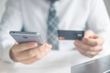 Genç işadamı onun elinde banka kredi kartıyla. Akıllı telefon ve Internet ticareti. Online ödeme telefon aracılığıyla. Online Döviz Alım Satım ticaret. Malların online ödeme.