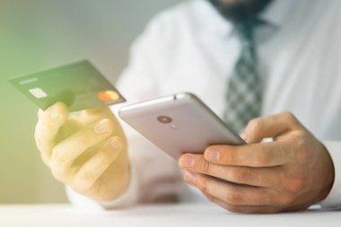 Genç işadamı onun elinde banka kredi kartıyla. Online ödeme telefon aracılığıyla. Malların online ödeme. Online Döviz Alım Satım ticaret. Akıllı telefon ve Internet ticaret.