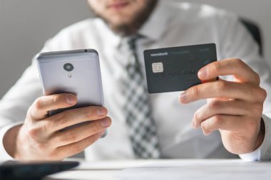 Akıllı telefon ve Internet ticareti. Genç işadamı onun elinde banka kredi kartıyla. Online Döviz Alım Satım ticaret. Malların online ödeme. Telefon aracılığıyla online ödeme.