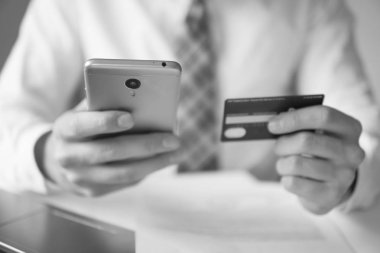 Online Döviz Alım Satım ticaret. Akıllı telefon ve Internet ticareti. telefon üzerinden ödeme. Genç işadamı onun elinde banka kredi kartıyla. Malların online ödeme.