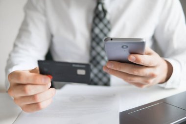 Genç işadamı onun elinde banka kredi kartıyla. Online Döviz Alım Satım ticaret. Malların online ödeme. Online ödeme telefon aracılığıyla. Akıllı telefon ve Internet ticaret.