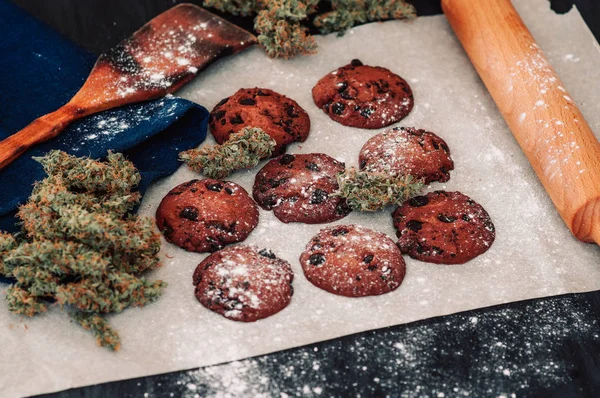 Bolachas de chocolate com marijuana. Doces com cannabis. Botões de canábis num fundo preto. Cozimento com a adição de CBD. Doces com erva daninha . — Fotografia de Stock