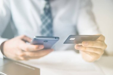 İşadamı kredi kartı ve bir akıllı telefon kullanır. Online alışveriş. Hareket eden telefon. Online ödeme. Office iş kavramı. Telefonu kapatın. Işık sızıntıları