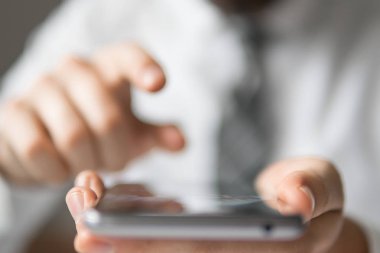 Akıllı telefon elinde tutuyor. Bir dizüstü bilgisayar ile ofis işleri. İş adamı iş bilgisayar ile ofis işleri tablo. Mali iş. Açık renkli. Genç işadamı sakallı.