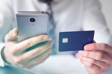İşadamı bir smartphone ve kredi kartı online ödeme için kullanır. Telefonu kapatın. Beyaz arka plan. Gönderen e-posta, hareket eden telefon. Online alışveriş. Office iş kavramı. Işık sızıntıları