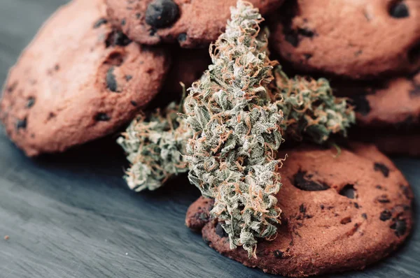 Doces com cannabis. Botões de canábis num fundo preto. Cozimento com a adição de CBD. Doces com erva. Biscoitos de chocolate com maconha . — Fotografia de Stock