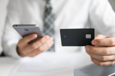 Akıllı telefon ve Internet ticareti. Malların online ödeme. Genç işadamı onun elinde banka kredi kartıyla. Online Döviz Alım Satım ticaret. Telefon aracılığıyla online ödeme.