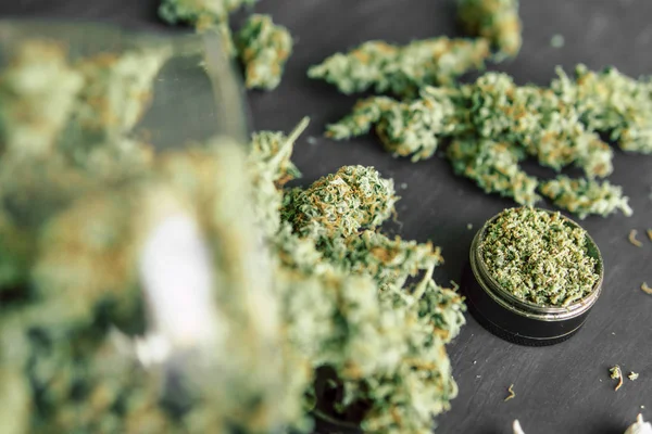 Marijuana bud flowers of cannabis. grinder and shredded cannabis joint and a packet of weed — Stock Photo, Image