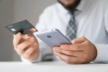 Genç işadamı onun elinde banka kredi kartıyla. Online Döviz Alım Satım ticaret. Akıllı telefon ve Internet ticareti. Online ödeme telefon aracılığıyla. Malların online ödeme.