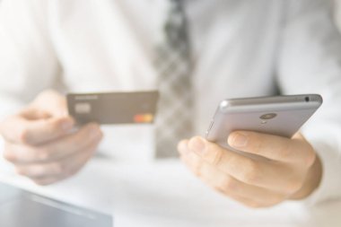 İşadamı online ödeme için kredi kartı ve bir akıllı telefon kullanır. Gönderen e-posta, hareket eden telefon. Beyaz arka plan. Office iş kavramı. Telefonu kapatın. Online alışveriş. Işık sızıntıları