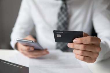 Online ödeme telefon aracılığıyla. Genç işadamı onun elinde banka kredi kartıyla. Malların online ödeme. Online Döviz Alım Satım ticaret. Akıllı telefon ve Internet ticaret.