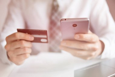 Akıllı telefon ve Internet ticareti. Malların online ödeme. Online ödeme telefon aracılığıyla. Genç işadamı onun elinde banka kredi kartıyla. Online Döviz Alım Satım ticaret.
