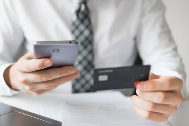 Online ödeme telefon aracılığıyla. Malların online ödeme. Genç işadamı onun elinde banka kredi kartıyla. Akıllı telefon ve Internet ticareti. Online Döviz Alım Satım ticaret.