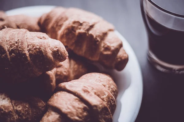 The concept of breakfast. Dessert and coffee. Mate moody color. Macro shot. American coffee and fresh croissants on a black background. — Stock Photo, Image