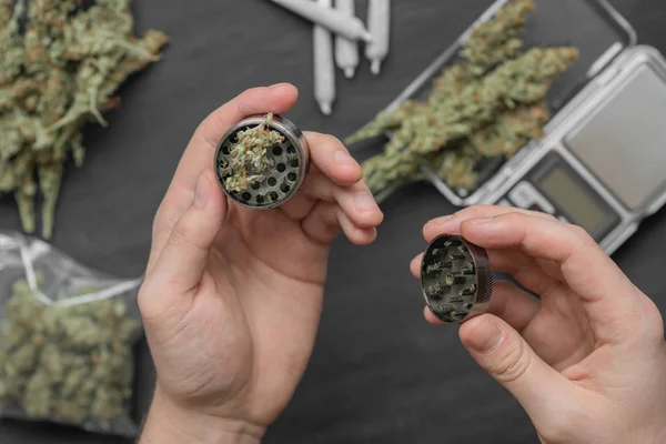 A man uses a grinder to grind marijuana weed — Stock Photo, Image