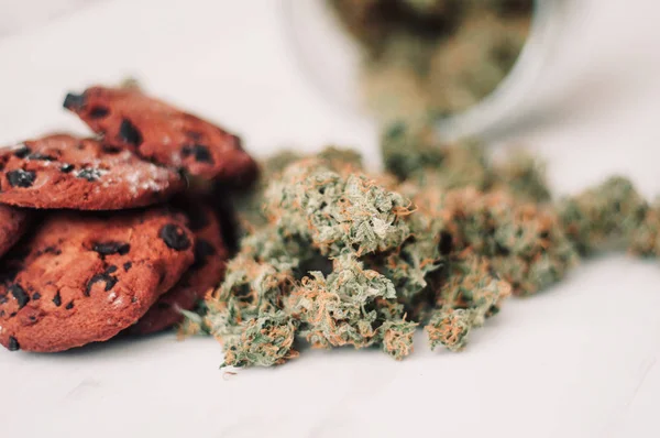 Cannabis buds on a black background. Baking with the addition of CBD. Sweets with weed. Chocolate cookies with marijuana. Sweets with cannabis.