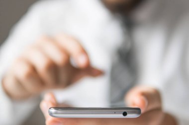 Bir dizüstü bilgisayar ile ofis işleri. İş adamı iş bilgisayar ile ofis işleri tablo. Mali iş. Açık renkli. Akıllı telefon elinde tutuyor. Genç işadamı sakallı.