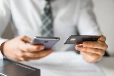 Malların online ödeme. Online Döviz Alım Satım ticaret. Akıllı telefon ve Internet ticareti. Online ödeme telefon aracılığıyla. Onun elinde banka kredi kartıyla genç işadamı.