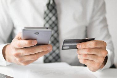 Akıllı telefon ve Internet ticareti. Online ödeme telefon aracılığıyla. Genç işadamı onun elinde banka kredi kartıyla. Malların online ödeme. Online Döviz Alım Satım ticaret.