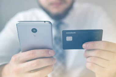 Akıllı telefon ve Internet ticareti. Genç işadamı onun elinde banka kredi kartıyla. Malların online ödeme. Online ödeme telefon aracılığıyla. Online Döviz Alım Satım ticaret.