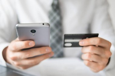 Malların internetten ödenmesi. Elinde banka kartı olan genç bir iş adamı. Çevrimiçi döviz ticareti. Akıllı telefon ve internet ticareti. Telefon üzerinden online ödemeler.
