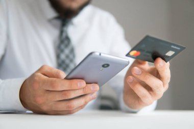 Online Döviz Alım Satım ticaret. Akıllı telefon ve Internet ticareti. Online ödeme telefon aracılığıyla. Malların online ödeme. Onun elinde banka kredi kartıyla genç işadamı.