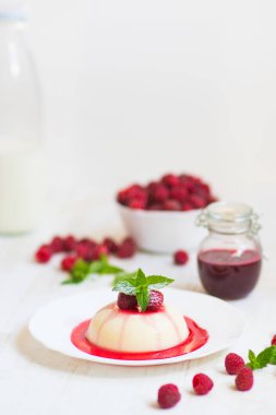 Dikey vurdu. Yaz tatlı. Açık renkli. Yakın çekim. Uçan pudra şekeri. Ahududu ve nane ile panakota.