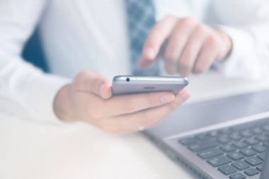 İş adamı iş bilgisayar ile ofis işleri tablo. Smartphone el genç işadamı sakallı. Yakın çekim. Açık renkli. Bir dizüstü bilgisayar ile ofis işleri. Mali iş.