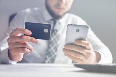 Genç işadamı onun elinde banka kredi kartıyla. Akıllı telefon ve Internet ticareti. Malların online ödeme. Online ödeme telefon aracılığıyla. Online Döviz Alım Satım ticaret.