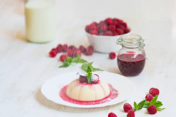 Flying powdered sugar. Panakota with raspberries and mint. Vertical shot. Summer dessert. Light background. Close up. — Stock Photo, Image