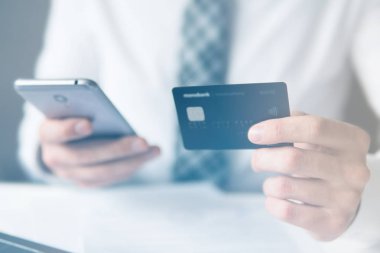 İşadamı online ödeme için kredi kartı ve akıllı telefon kullanır. Online alışveriş. Telefonu kapat. Ofis iş konsepti. Cep telefonu. ışık sızıntıları