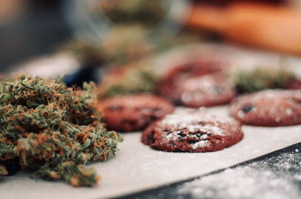 Cannabis knoppar på en svart bakgrund. Bakning med tillägg av Cbd. godis med ogräs. Choklad cookies med marijuana. Godis med cannabis. — Stockfoto