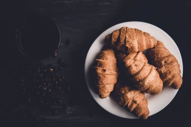 Kahvaltı kavramı. Tatlı ve kahve. Moody renk dostum. Siyah bir zemin üzerine üstten görünüm taze kruvasan ve kahve. Makro çekim.
