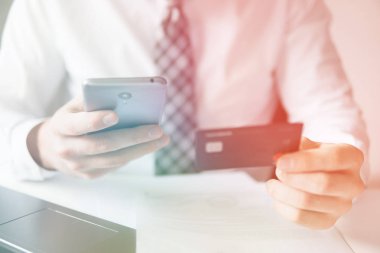 Online Döviz Alım Satım ticaret. Genç işadamı onun elinde banka kredi kartıyla. Online ödeme telefon aracılığıyla. Malların online ödeme. Akıllı telefon ve Internet ticaret.